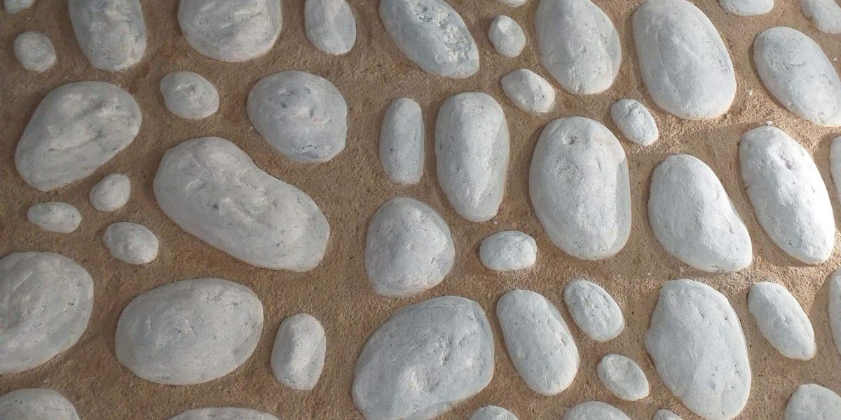 Detalle de pared decorativa con textura de piedras redondeadas blancas.