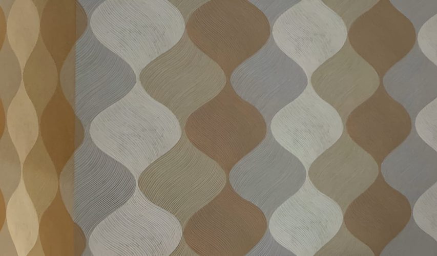 Diseño de pared con papel pintado geométrico en tonos beige, marrón y gris.