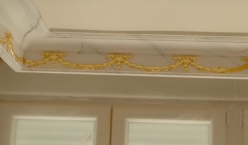 Detalle de moldura de techo decorada con pan de oro en vivienda clásica.