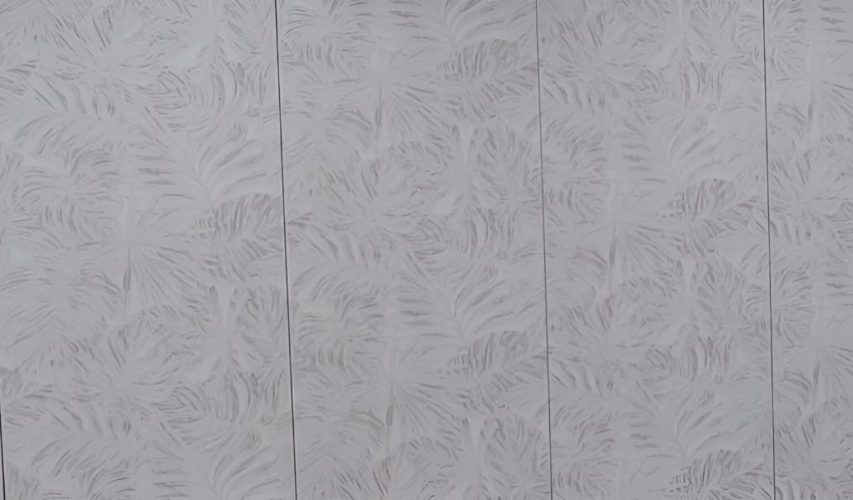 Pared de dormitorio decorada con papel pintado de hojas blancas y muebles modernos.
